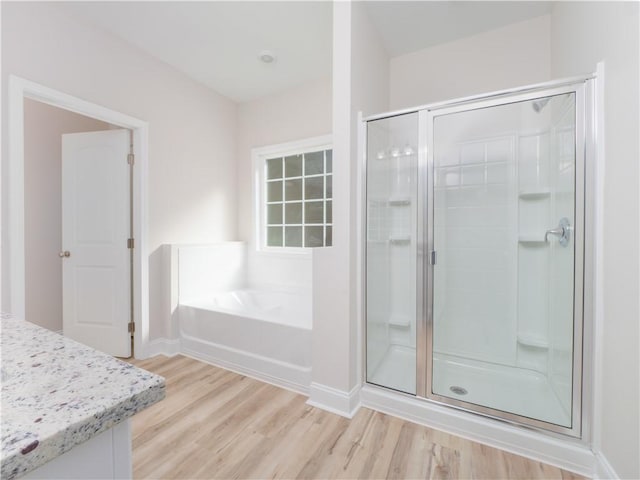 bathroom featuring hardwood / wood-style flooring and plus walk in shower