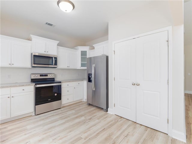 kitchen featuring appliances with stainless steel finishes, light hardwood / wood-style floors, and white cabinetry