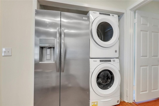 laundry room with hardwood / wood-style flooring and stacked washer and clothes dryer