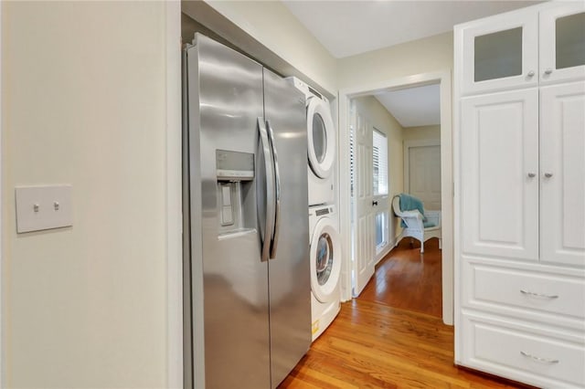 kitchen with white cabinets, stainless steel fridge, light hardwood / wood-style floors, and stacked washing maching and dryer