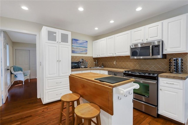 kitchen with dark hardwood / wood-style flooring, stainless steel appliances, sink, white cabinets, and a center island