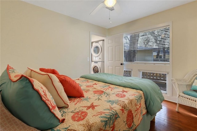 bedroom with ceiling fan, stacked washer and dryer, and wood-type flooring