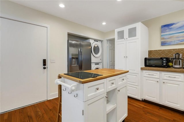 kitchen with white cabinets, stacked washing maching and dryer, stainless steel refrigerator with ice dispenser, and wooden counters