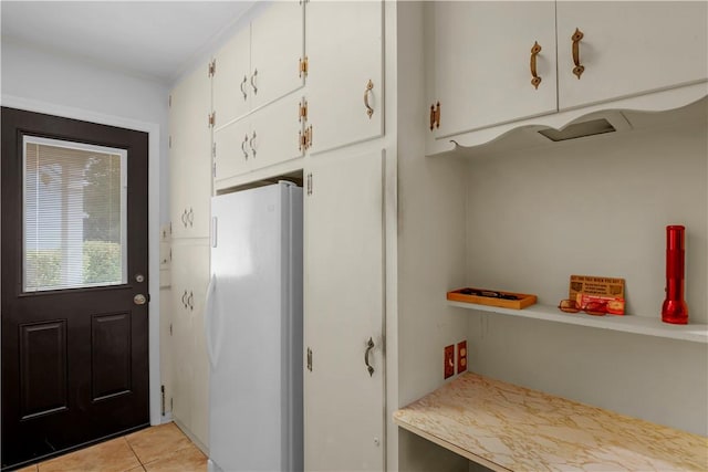1001 Coral Rd, Waycross, GA 31501 - kitchen with freestanding refrigerator, white cabinets, light tile patterned floors, light countertops, and ornamental molding