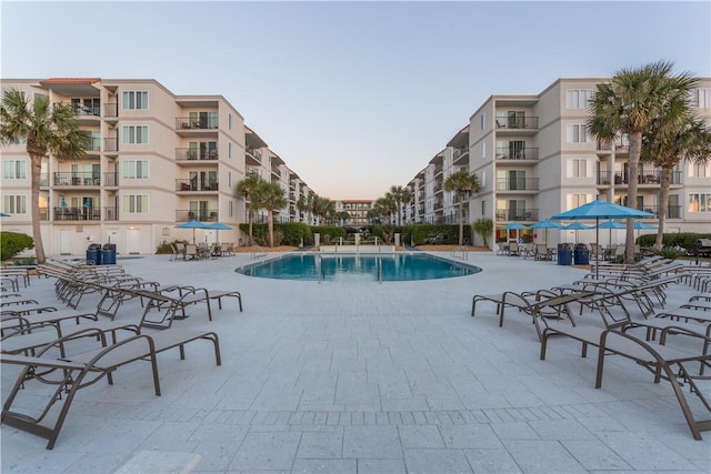 pool at dusk with a patio and a community pool