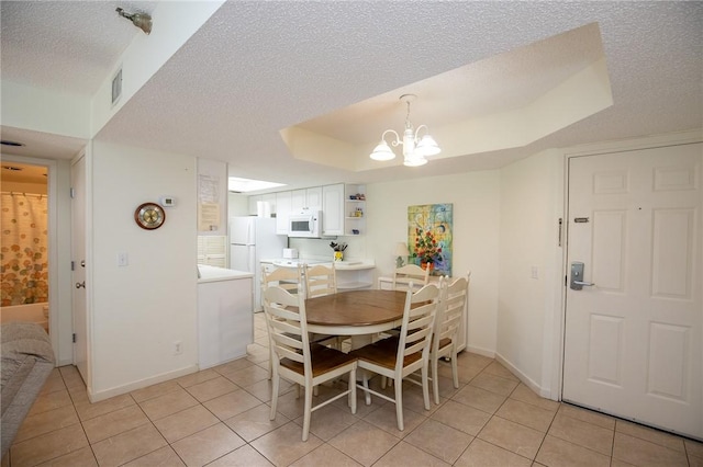 dining room featuring baseboards, a chandelier, light tile patterned flooring, a textured ceiling, and a raised ceiling