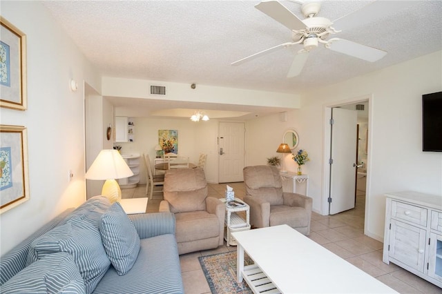 living area with light tile patterned flooring, visible vents, ceiling fan with notable chandelier, and a textured ceiling