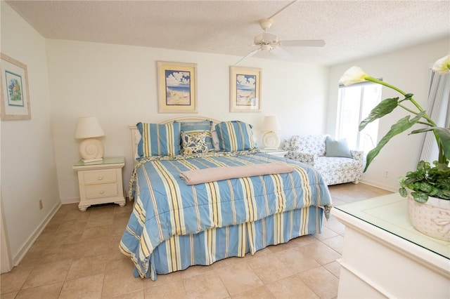 bedroom with ceiling fan, light tile patterned floors, baseboards, and a textured ceiling