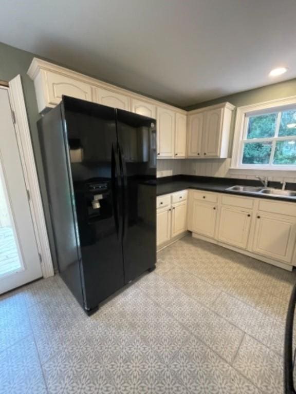 kitchen featuring black fridge with ice dispenser, light tile patterned flooring, and sink