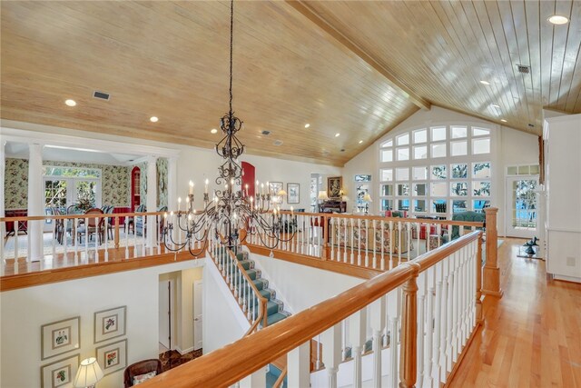 hallway featuring light hardwood / wood-style floors, beamed ceiling, wooden ceiling, and a notable chandelier