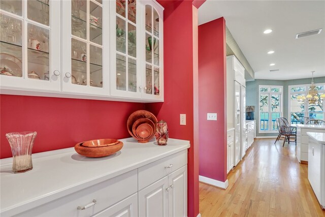 kitchen with a chandelier, pendant lighting, light hardwood / wood-style flooring, and white cabinetry