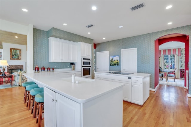 kitchen featuring kitchen peninsula, sink, white cabinets, and light hardwood / wood-style floors