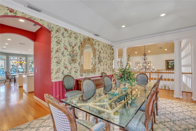 dining room with ornate columns, ornamental molding, a chandelier, and light hardwood / wood-style floors