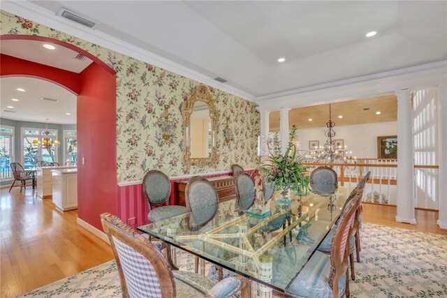 dining room with ornate columns, ornamental molding, a chandelier, and light hardwood / wood-style floors