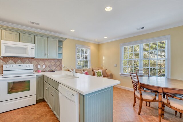 kitchen with kitchen peninsula, white appliances, a wealth of natural light, and sink