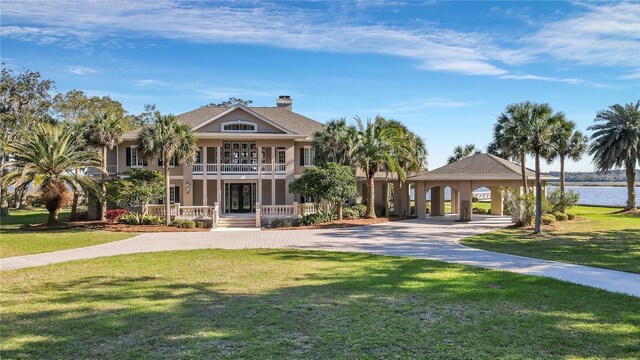 view of front of home with a front yard, a porch, a water view, and a carport