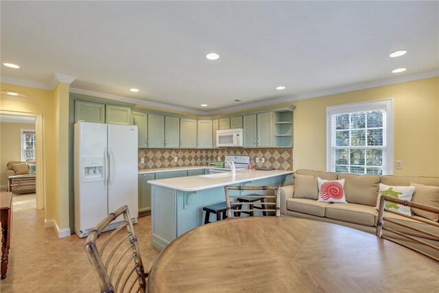 kitchen featuring white appliances, backsplash, green cabinetry, light tile patterned flooring, and kitchen peninsula