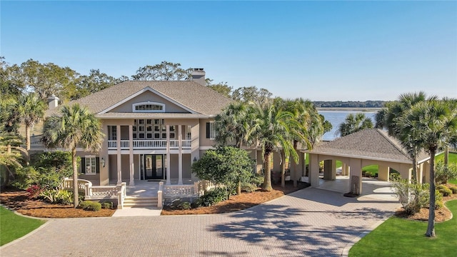 view of front facade with covered porch, a water view, a carport, and a balcony