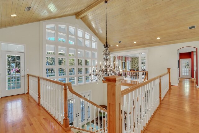 hallway with beam ceiling, light hardwood / wood-style floors, an inviting chandelier, and wooden ceiling