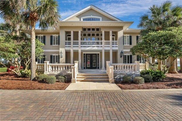 view of front of property with french doors, a balcony, and covered porch