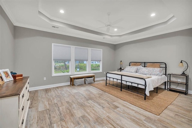 bedroom with light wood-style floors, baseboards, and a tray ceiling