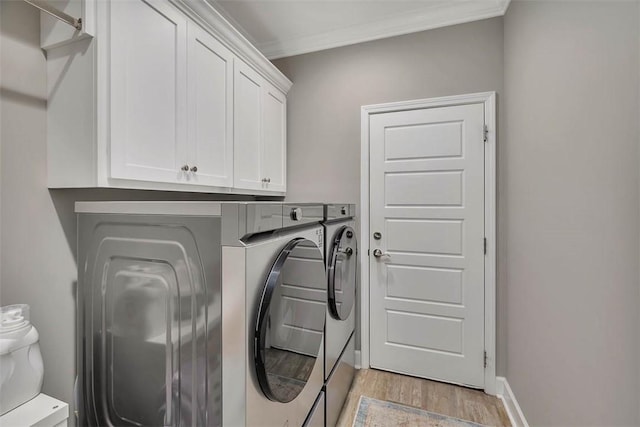 laundry room featuring baseboards, light wood-type flooring, cabinet space, washing machine and clothes dryer, and crown molding