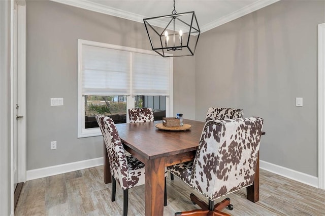 dining area featuring a notable chandelier, ornamental molding, wood finished floors, and baseboards