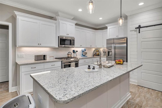 kitchen featuring a barn door, white cabinetry, stainless steel appliances, and crown molding