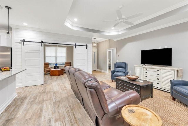 living area with crown molding, light wood finished floors, a raised ceiling, a barn door, and ceiling fan