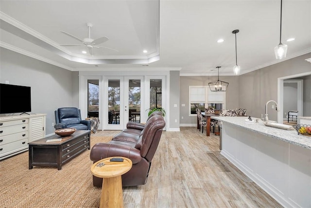 living room featuring light wood-type flooring, a tray ceiling, crown molding, and recessed lighting