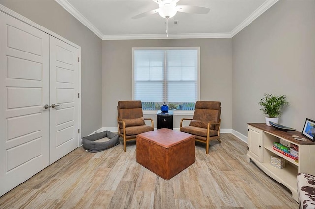 sitting room featuring light wood-style floors, ornamental molding, baseboards, and a ceiling fan