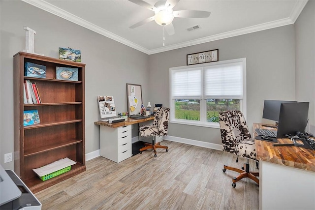 home office with light wood-style flooring, visible vents, a ceiling fan, baseboards, and ornamental molding