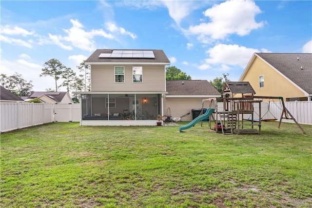 rear view of house featuring a lawn, a playground, a fenced backyard, and a sunroom