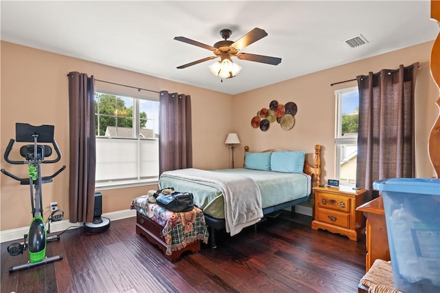 bedroom with ceiling fan, wood finished floors, visible vents, and baseboards