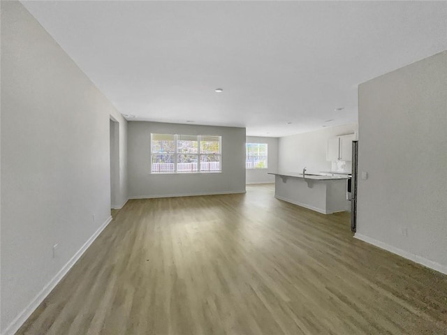 unfurnished living room with baseboards and light wood-type flooring