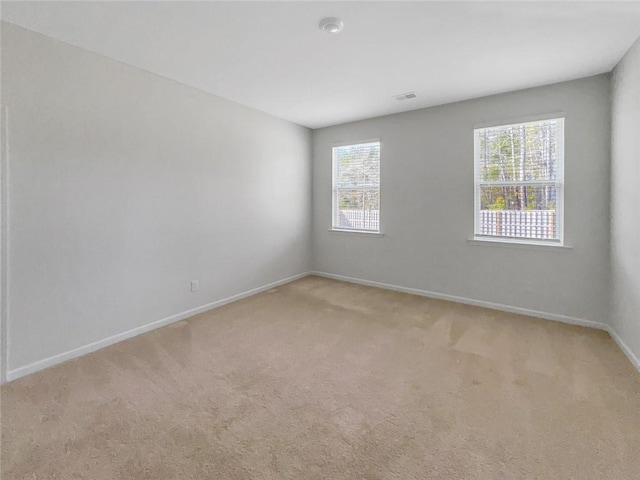 empty room featuring baseboards, light carpet, and visible vents