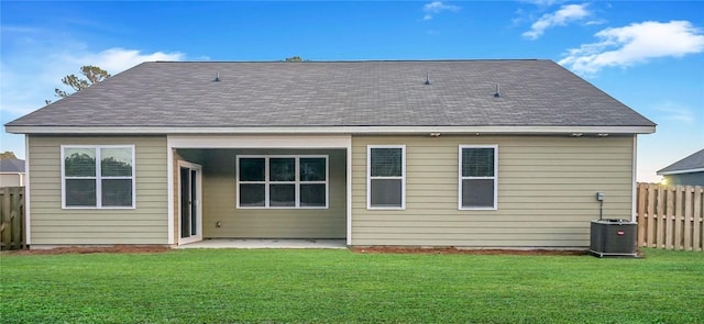 back of house with cooling unit, a lawn, fence, and roof with shingles