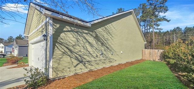 view of side of property featuring a yard, an attached garage, and fence