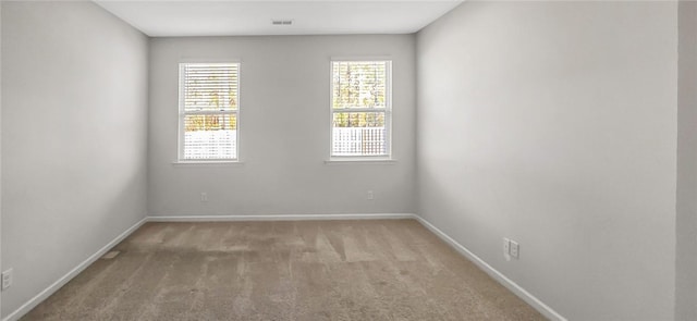 empty room featuring visible vents, baseboards, and light colored carpet