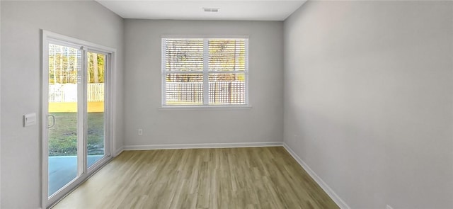 empty room featuring visible vents, baseboards, and wood finished floors