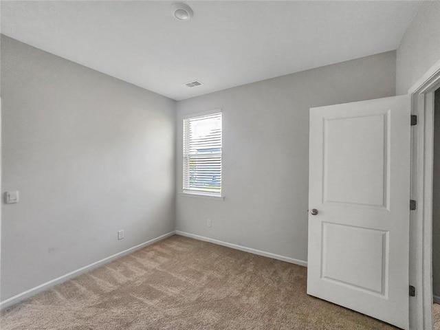 carpeted spare room with visible vents and baseboards