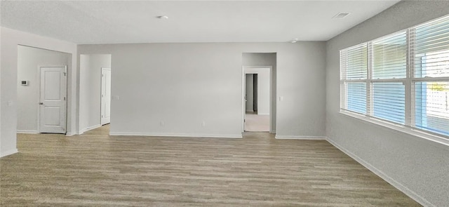 unfurnished room featuring visible vents, baseboards, and wood finished floors