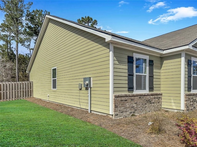 view of home's exterior featuring brick siding, a yard, and fence