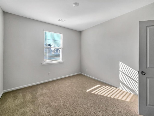 empty room with carpet, visible vents, and baseboards