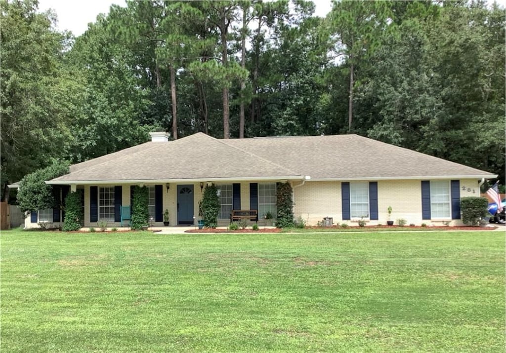 281 Cambridge Cir, Kingsland, GA 31548 - ranch-style home with covered porch, a front yard, a chimney, and view of wooded area