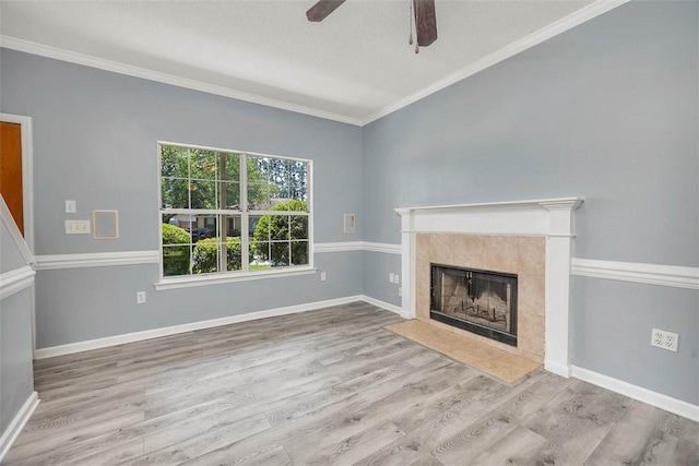 unfurnished living room with a tile fireplace, wood finished floors, baseboards, ceiling fan, and ornamental molding