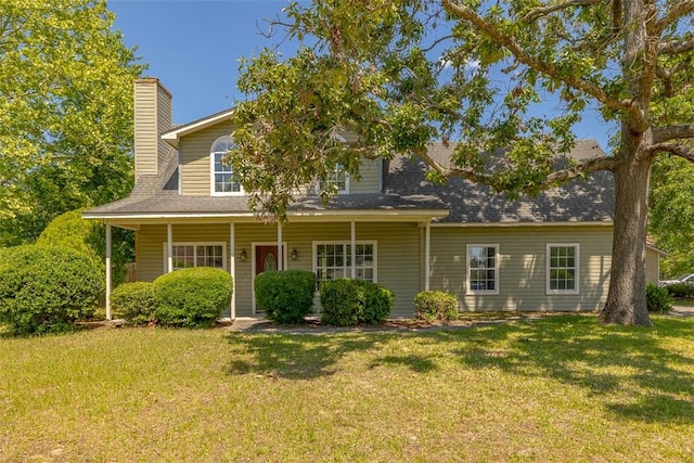 view of front of property featuring a chimney, a front yard, roof with shingles, and covered porch