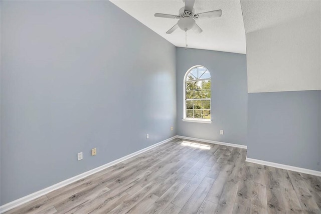 unfurnished room with vaulted ceiling, wood finished floors, baseboards, and ceiling fan