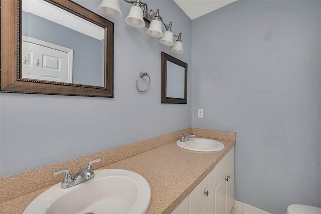bathroom featuring toilet, double vanity, and a sink