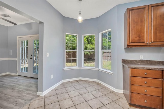 unfurnished dining area featuring baseboards, a ceiling fan, and french doors
